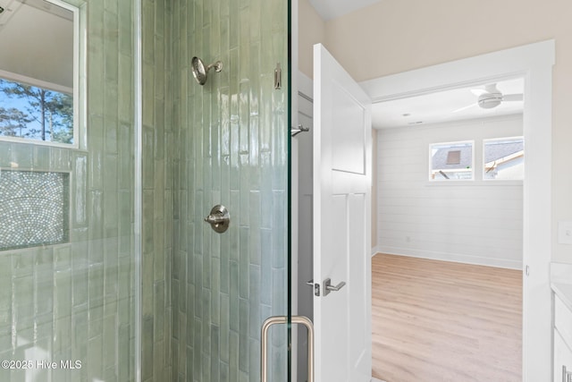 full bath featuring baseboards, a stall shower, and wood finished floors