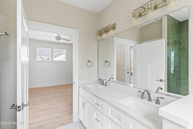 bathroom featuring a ceiling fan, baseboards, a sink, and wood finished floors