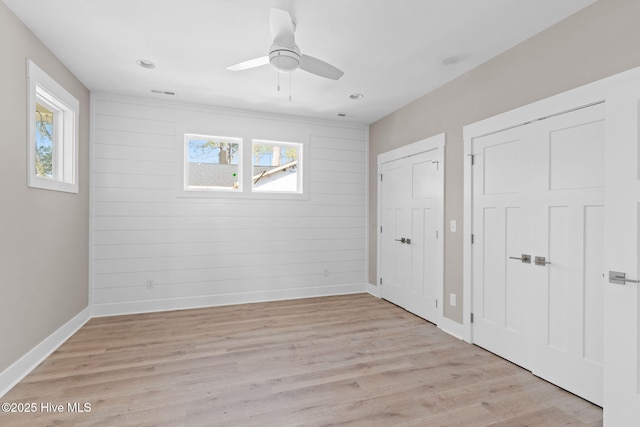 unfurnished bedroom with baseboards, multiple closets, and multiple windows