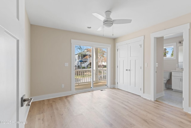 unfurnished bedroom with access to outside, multiple windows, light wood-type flooring, and visible vents