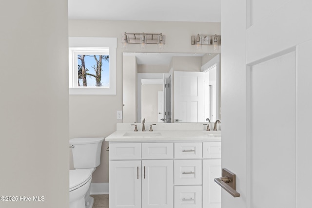 full bath featuring a sink, baseboards, toilet, and double vanity