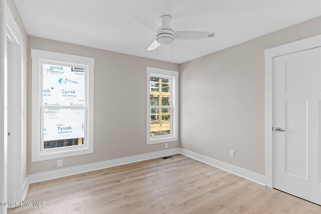 spare room with a ceiling fan, baseboards, and light wood finished floors