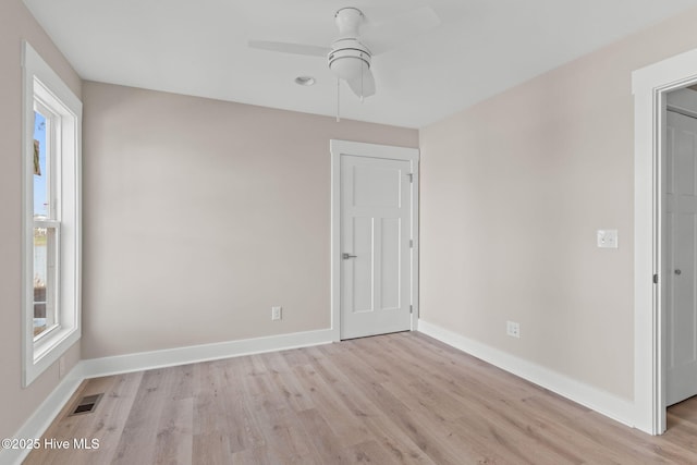 empty room featuring baseboards, ceiling fan, and light wood finished floors