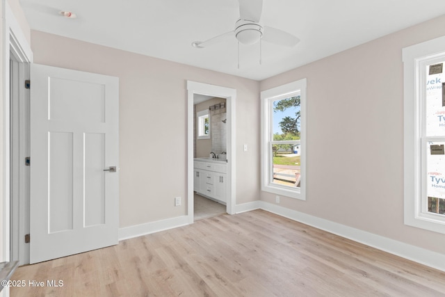 unfurnished bedroom with light wood-style floors, connected bathroom, baseboards, and multiple windows