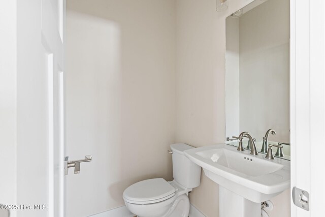 bathroom with toilet, baseboards, and a sink