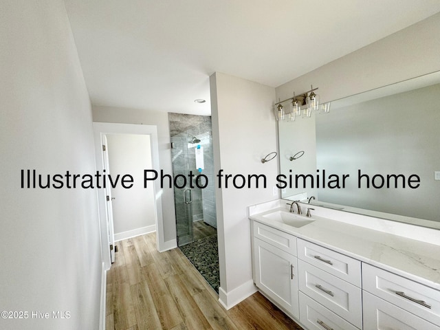 full bathroom featuring a stall shower, baseboards, wood finished floors, and vanity