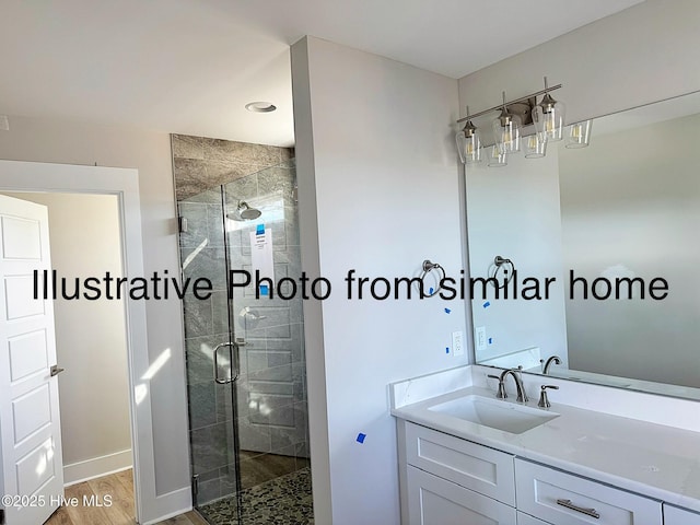 bathroom featuring a stall shower, vanity, baseboards, and wood finished floors