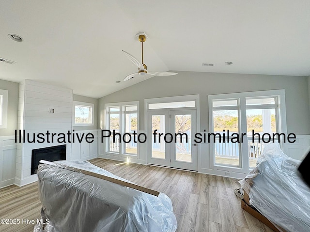 bedroom with lofted ceiling, light wood-style flooring, a large fireplace, visible vents, and access to exterior