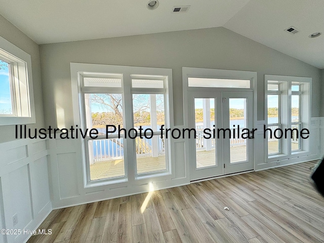 doorway to outside featuring light wood-style flooring, visible vents, vaulted ceiling, and french doors