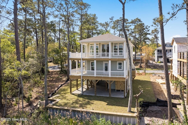 back of property with a deck, a balcony, a yard, a patio, and a shingled roof