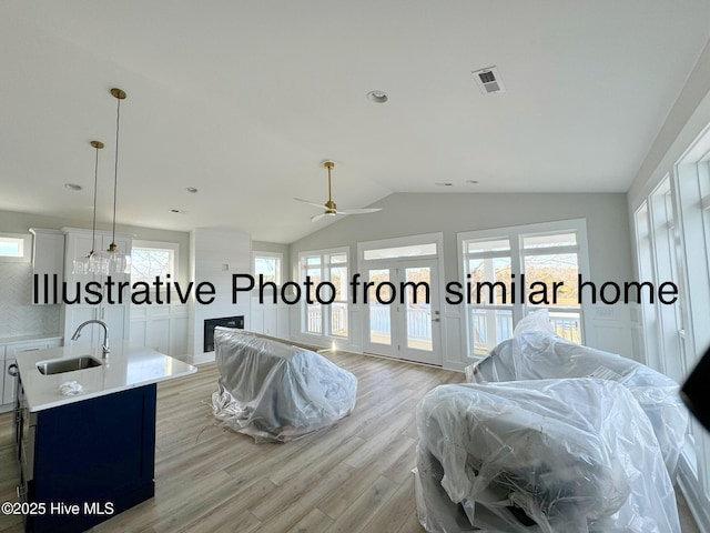 kitchen with lofted ceiling, a wealth of natural light, light countertops, visible vents, and a sink