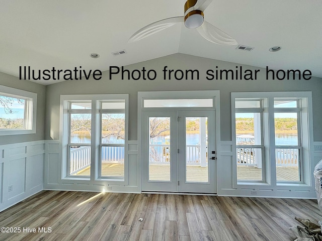 doorway to outside featuring visible vents, vaulted ceiling, light wood-style flooring, and a water view