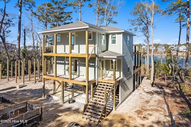 view of front of home with board and batten siding, roof with shingles, and stairway