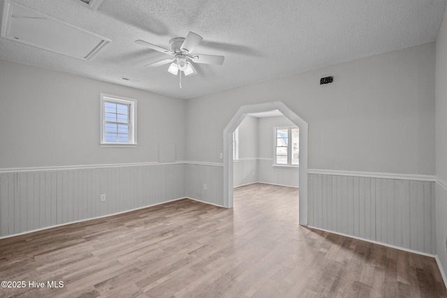 spare room with ceiling fan, light hardwood / wood-style floors, and a textured ceiling