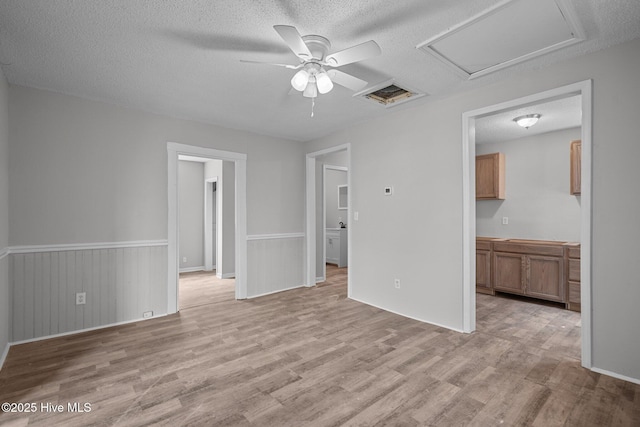 empty room featuring ceiling fan, a textured ceiling, and light hardwood / wood-style flooring