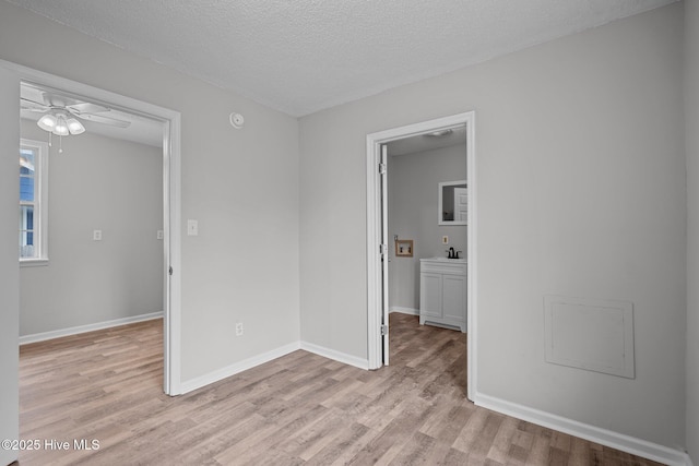 unfurnished room featuring ceiling fan, sink, a textured ceiling, and light wood-type flooring