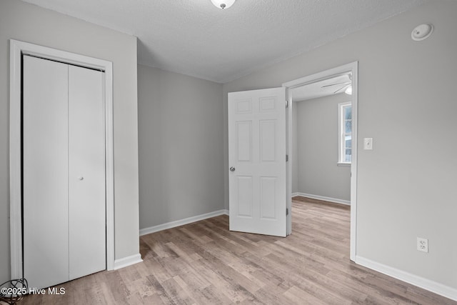 unfurnished bedroom with a textured ceiling, a closet, and light wood-type flooring