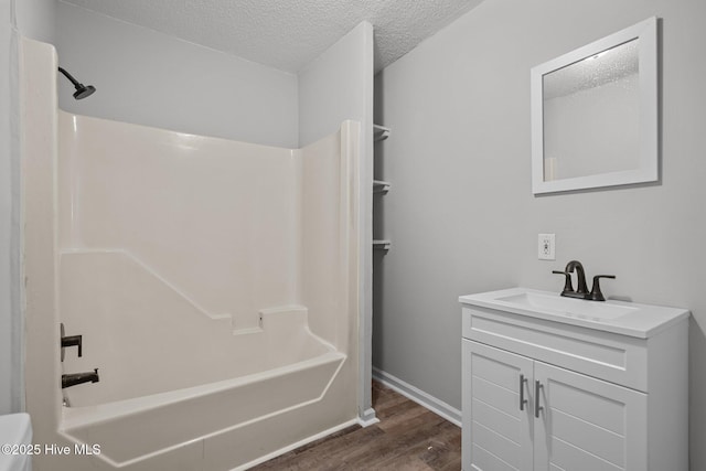 bathroom with washtub / shower combination, a textured ceiling, hardwood / wood-style flooring, and vanity