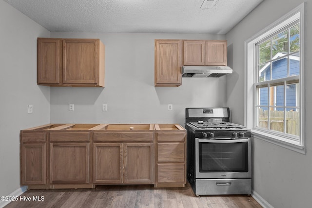 kitchen featuring a textured ceiling, gas stove, and light wood-type flooring