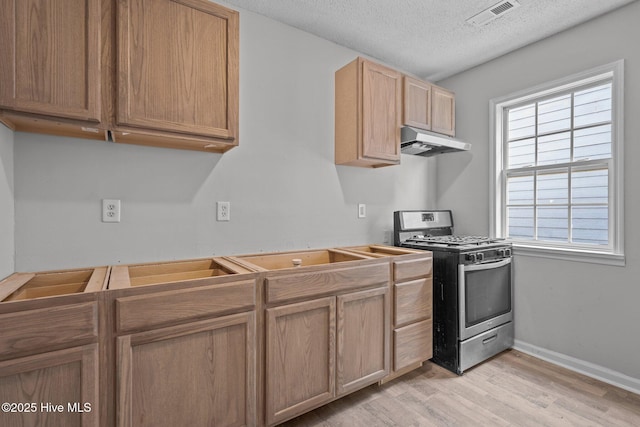 kitchen with plenty of natural light, stainless steel range with gas cooktop, a textured ceiling, and light hardwood / wood-style floors