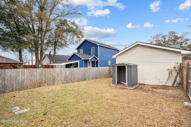 back of house with a shed and a yard