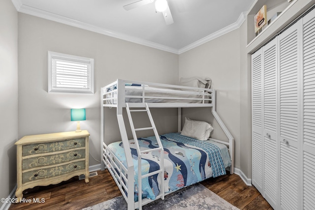 bedroom with crown molding, dark hardwood / wood-style floors, ceiling fan, and a closet