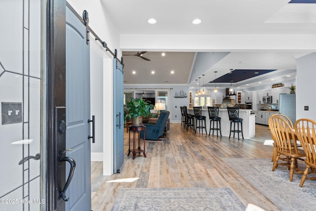 entryway featuring a barn door, light wood-type flooring, and a tray ceiling