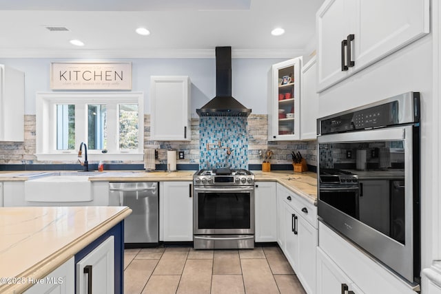 kitchen featuring white cabinetry, light stone counters, ornamental molding, appliances with stainless steel finishes, and exhaust hood