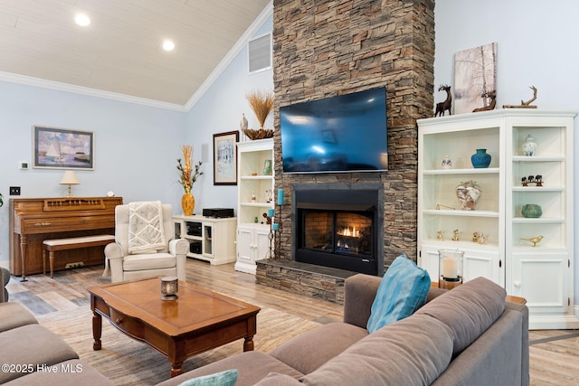 living room featuring lofted ceiling, wood ceiling, ornamental molding, a stone fireplace, and light wood-type flooring