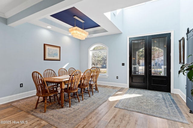 dining room featuring an inviting chandelier, crown molding, wood-type flooring, and french doors