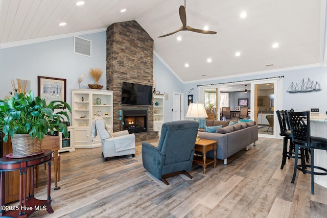 living room with a stone fireplace, crown molding, high vaulted ceiling, light wood-type flooring, and ceiling fan