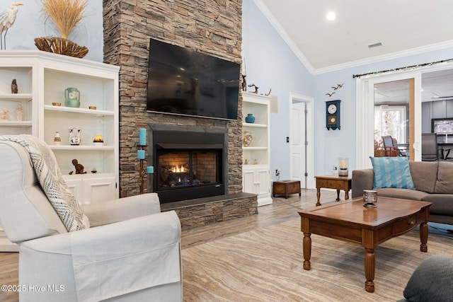 living room featuring crown molding, vaulted ceiling, a fireplace, and light hardwood / wood-style flooring