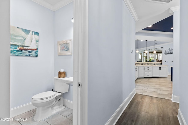 bathroom featuring vanity, wood-type flooring, ornamental molding, and toilet