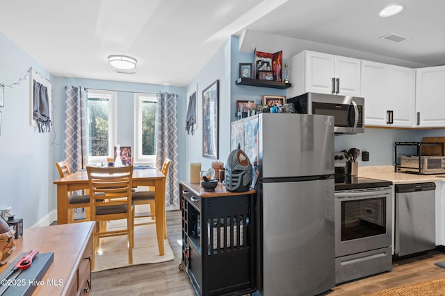 kitchen with white cabinetry, appliances with stainless steel finishes, and light hardwood / wood-style floors