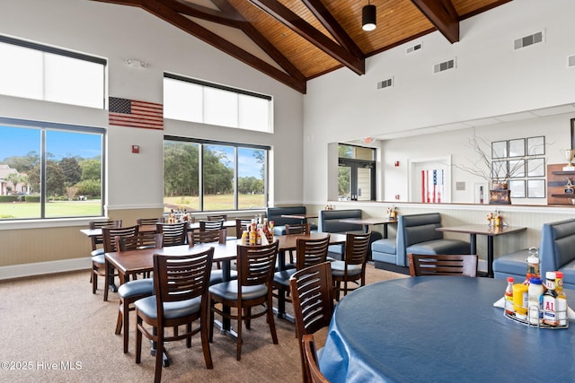 carpeted dining area featuring plenty of natural light, beam ceiling, high vaulted ceiling, and wooden ceiling