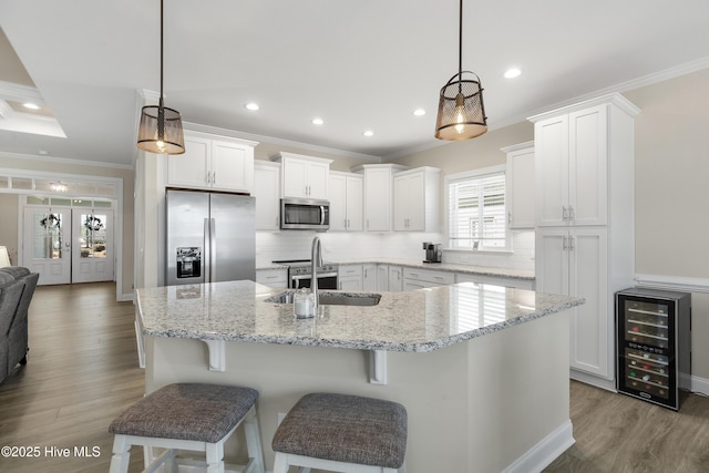 kitchen featuring decorative light fixtures, white cabinets, stainless steel appliances, and wine cooler