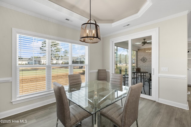 dining room featuring ceiling fan, dark hardwood / wood-style flooring, a tray ceiling, and ornamental molding