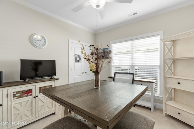 carpeted dining room with ceiling fan, crown molding, and plenty of natural light