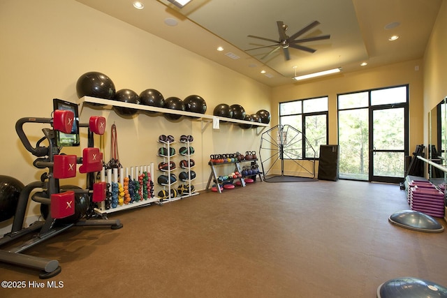 gym featuring ceiling fan and a tray ceiling