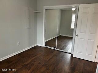 unfurnished bedroom with dark hardwood / wood-style floors and a closet