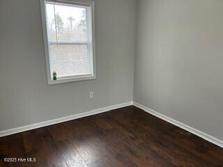 spare room with a wealth of natural light and dark hardwood / wood-style floors