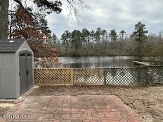 view of patio / terrace featuring a water view and a storage unit