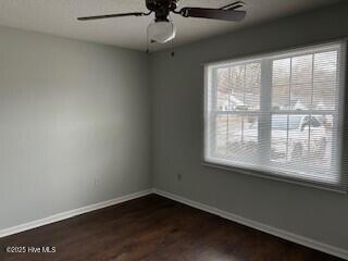 unfurnished room featuring ceiling fan, a healthy amount of sunlight, and dark hardwood / wood-style floors