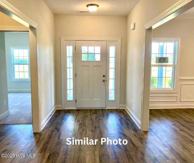 foyer with a textured ceiling, dark hardwood / wood-style flooring, and crown molding