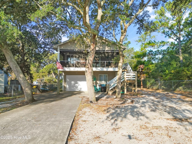 raised beach house with a garage, a wooden deck, and a sunroom