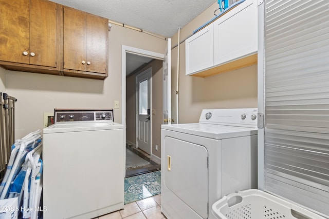 clothes washing area featuring cabinets, separate washer and dryer, a textured ceiling, and light tile patterned floors