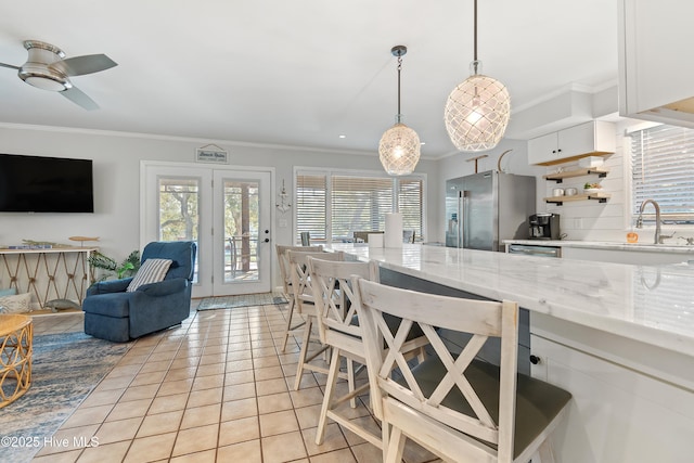 kitchen with light tile patterned floors, sink, white cabinetry, hanging light fixtures, and high end refrigerator