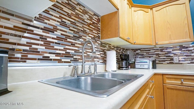 kitchen featuring light countertops, light brown cabinetry, a sink, and decorative backsplash