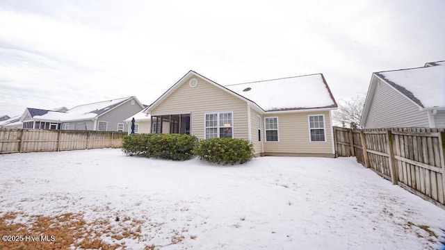 snow covered house with a fenced backyard