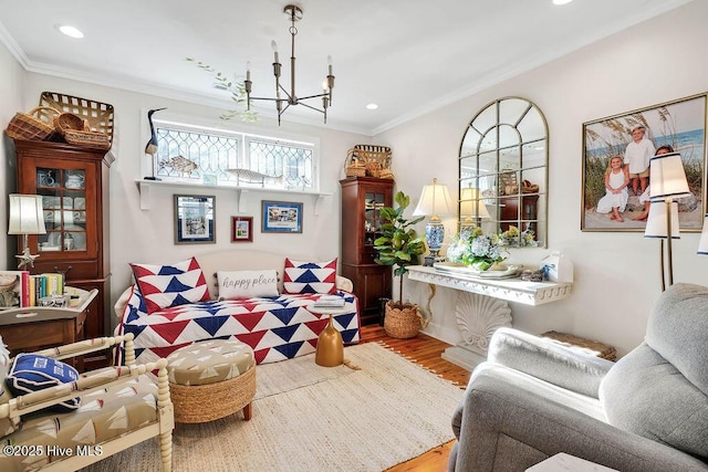 living area featuring an inviting chandelier, ornamental molding, and wood-type flooring